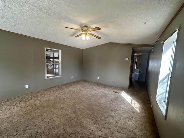 carpeted empty room featuring a textured ceiling, ceiling fan, and vaulted ceiling