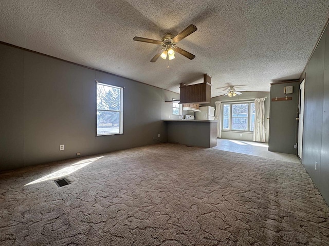 unfurnished living room featuring visible vents, carpet floors, ceiling fan, vaulted ceiling, and a textured ceiling