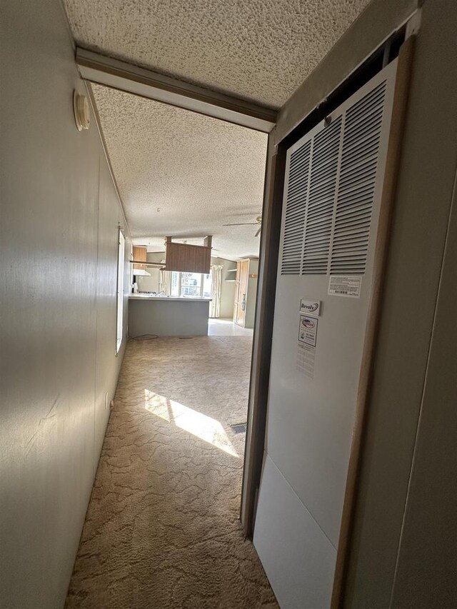 hall featuring carpet flooring, a heating unit, and a textured ceiling