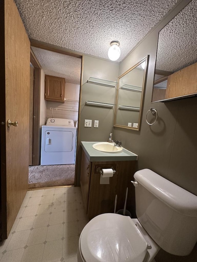 half bathroom with tile patterned floors, toilet, washer / clothes dryer, a textured ceiling, and vanity