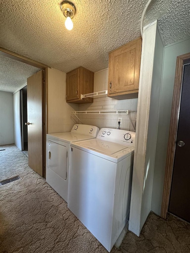 clothes washing area featuring visible vents, light carpet, washer and dryer, a textured ceiling, and cabinet space