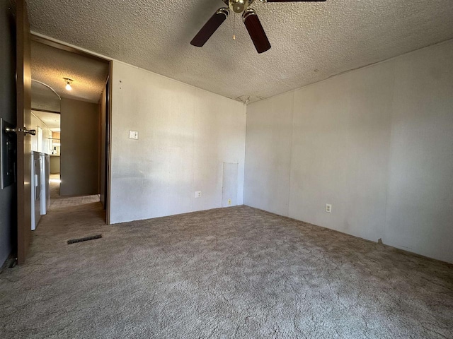 carpeted empty room with visible vents, a textured ceiling, and a ceiling fan