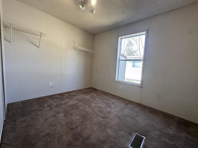 carpeted spare room with visible vents and a textured ceiling