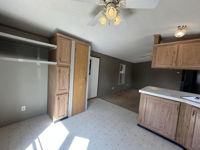 kitchen featuring a ceiling fan, light countertops, light floors, and a textured ceiling