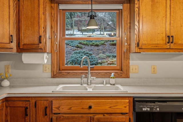 kitchen featuring a sink, light countertops, pendant lighting, dishwasher, and brown cabinets