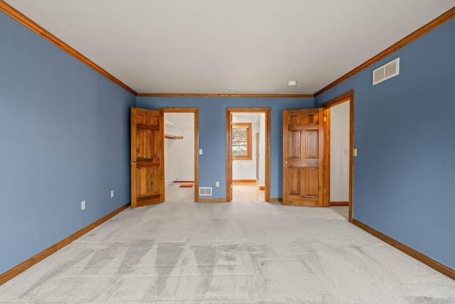 unfurnished bedroom with visible vents, baseboards, light colored carpet, and a spacious closet