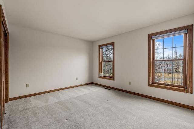 empty room featuring baseboards and light carpet