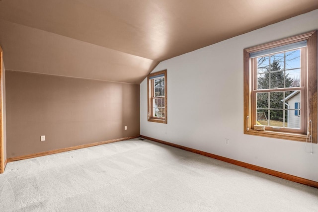 additional living space with vaulted ceiling, baseboards, and light carpet