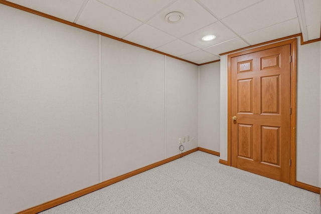 below grade area featuring a drop ceiling, carpet floors, and baseboards