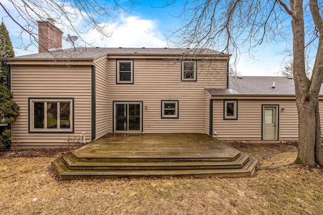 back of property with a chimney and a deck