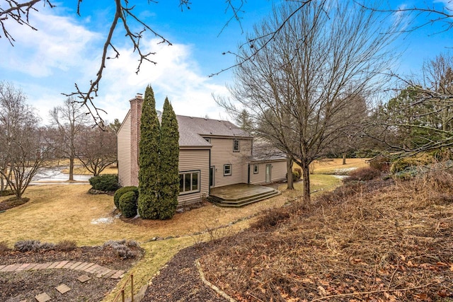 rear view of property with a chimney and roof with shingles