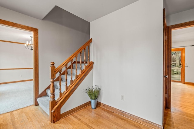 stairway with a chandelier, baseboards, and wood finished floors