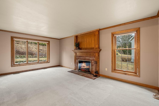 unfurnished living room with light colored carpet, a brick fireplace, baseboards, and ornamental molding