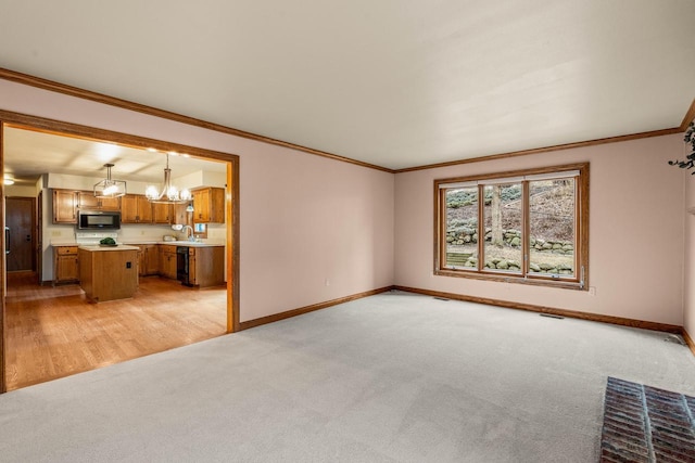 unfurnished living room featuring baseboards, light carpet, an inviting chandelier, and ornamental molding