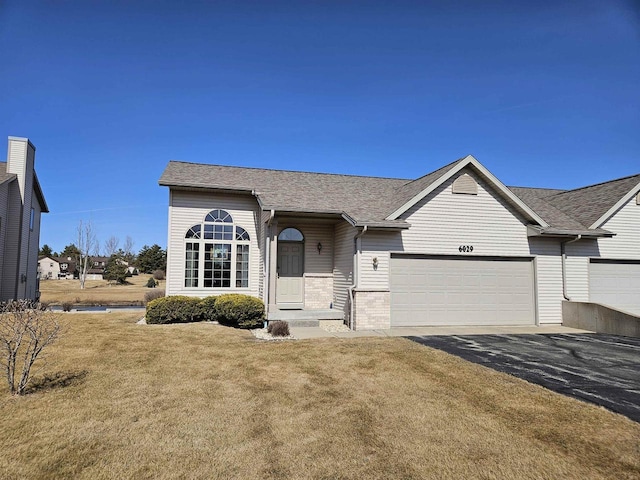 single story home featuring aphalt driveway, a shingled roof, a front yard, an attached garage, and brick siding