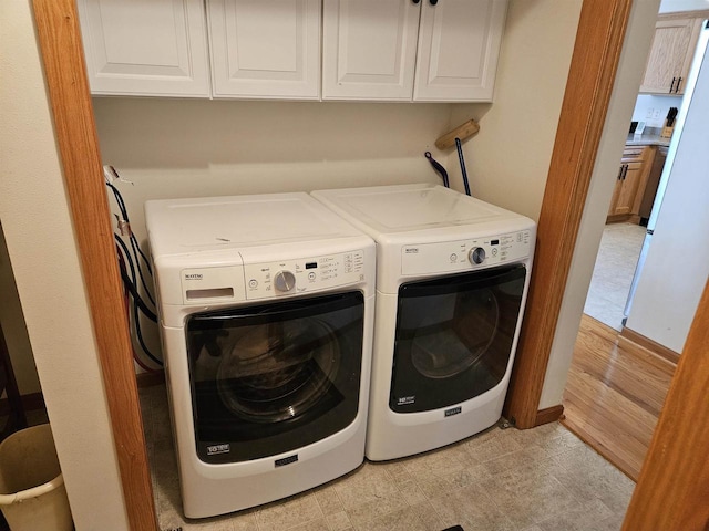 laundry area with cabinet space, separate washer and dryer, and light floors