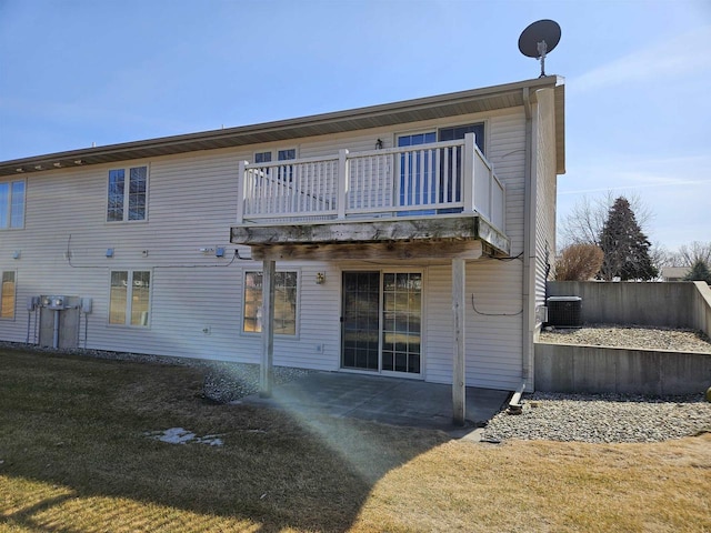 rear view of property featuring a lawn, a patio, central AC, fence, and a balcony