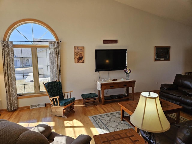 living room featuring visible vents, light wood-style flooring, baseboards, and vaulted ceiling