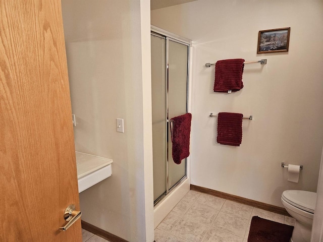 bathroom with tile patterned floors, baseboards, toilet, and a shower stall