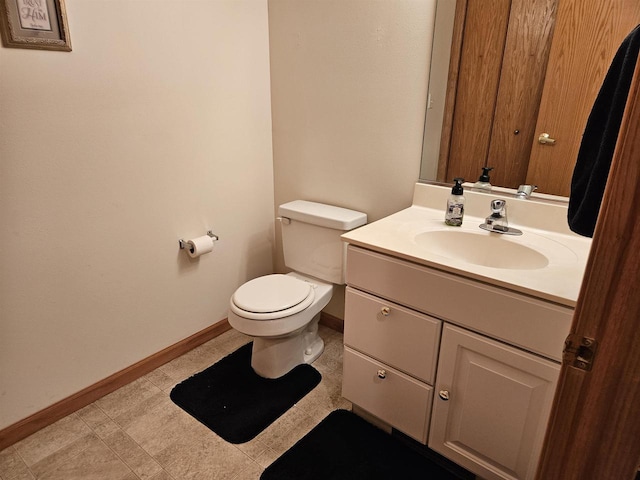 bathroom with baseboards, toilet, and vanity