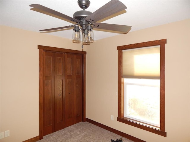 unfurnished bedroom with a ceiling fan, baseboards, a closet, and light carpet