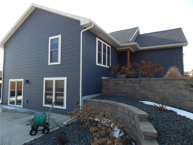 rear view of house featuring a patio and a shingled roof