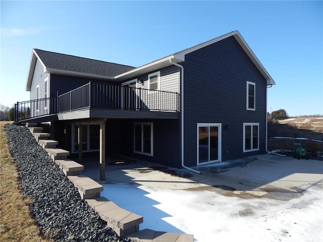 rear view of house with a wooden deck and a patio