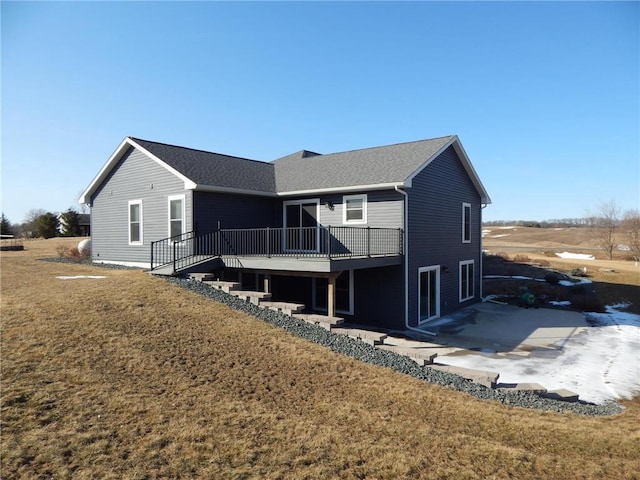 back of property with a patio, a lawn, a deck, and a shingled roof