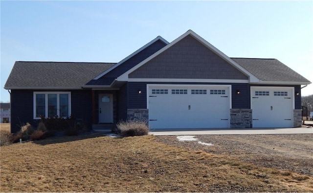 craftsman-style house with an attached garage, stone siding, and driveway