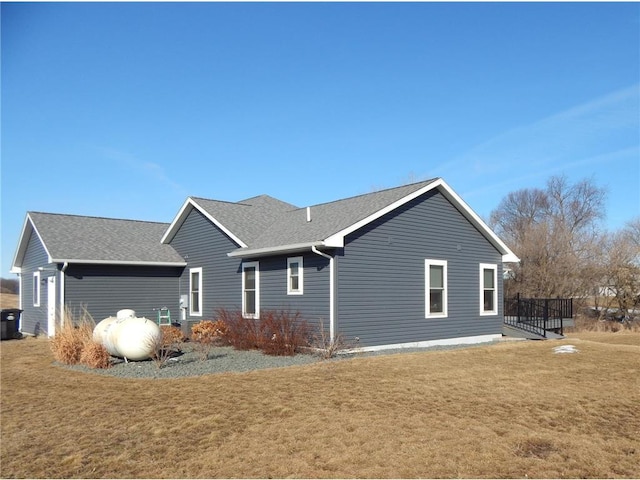 view of home's exterior featuring a lawn, a shingled roof, and a deck