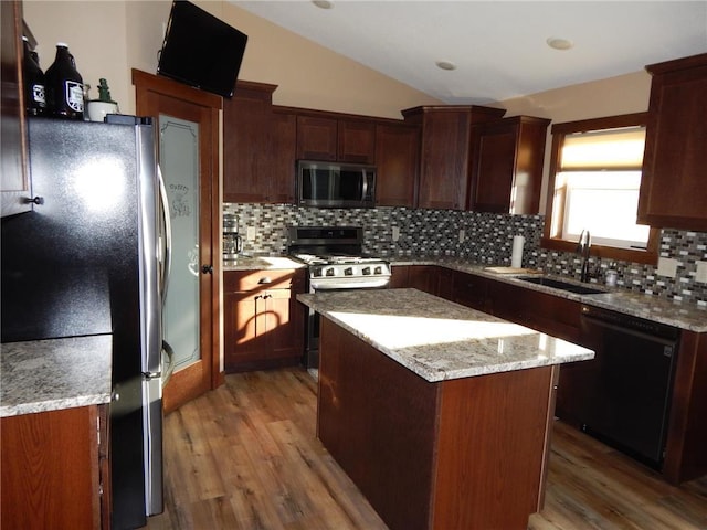 kitchen featuring a sink, a center island, stainless steel appliances, decorative backsplash, and lofted ceiling