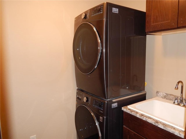 laundry room with a sink, cabinet space, and stacked washer and dryer