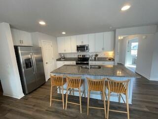 kitchen with an island with sink, dark wood finished floors, white cabinetry, recessed lighting, and appliances with stainless steel finishes