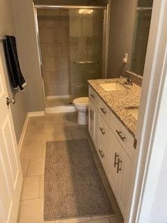 full bathroom featuring vanity, baseboards, a stall shower, tile patterned flooring, and toilet