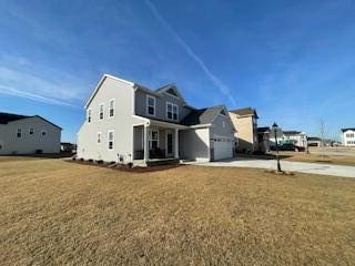 rear view of property featuring concrete driveway, covered porch, a lawn, and a garage