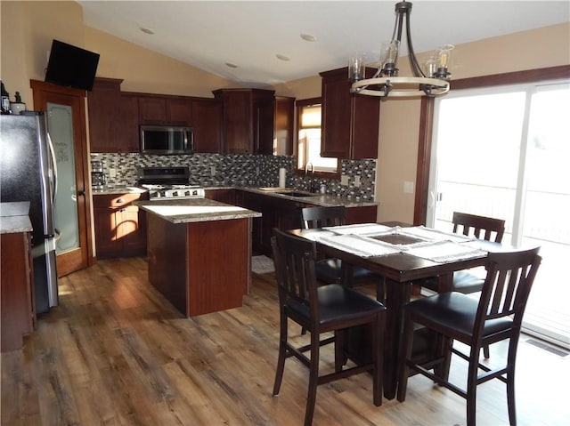 kitchen with backsplash, a center island, lofted ceiling, appliances with stainless steel finishes, and wood finished floors