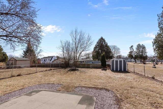 view of yard featuring a patio, a storage unit, a fenced backyard, and an outbuilding