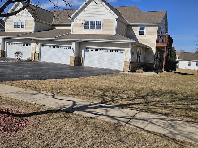 view of front of property featuring brick siding, aphalt driveway, a front yard, roof with shingles, and a garage