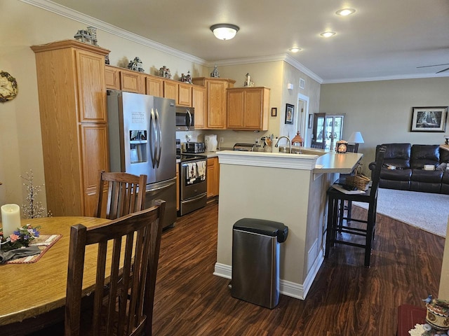 kitchen with dark wood-type flooring, crown molding, open floor plan, a breakfast bar area, and appliances with stainless steel finishes