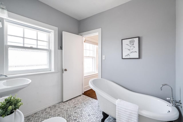 full bath with a soaking tub and baseboards