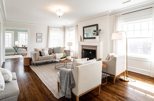 living room with a tile fireplace, crown molding, baseboards, and hardwood / wood-style flooring