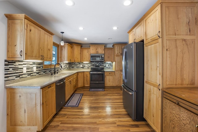 kitchen with light brown cabinets, decorative backsplash, appliances with stainless steel finishes, wood finished floors, and a sink