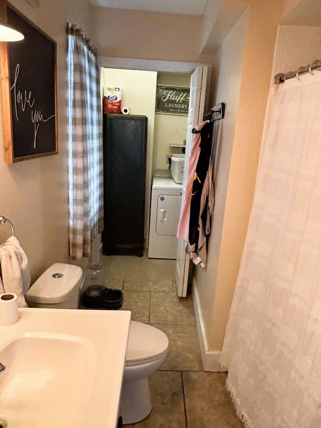 bathroom with tile patterned floors, washer / dryer, curtained shower, and toilet