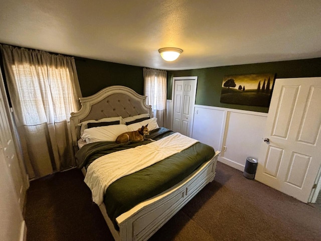 carpeted bedroom with a closet and wainscoting