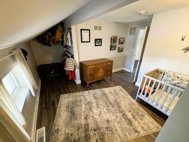 bedroom with dark wood-style floors, visible vents, and baseboards