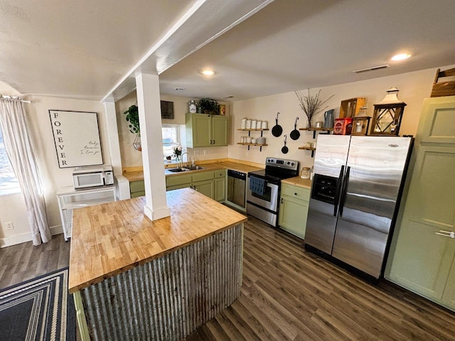 kitchen with green cabinets, a sink, appliances with stainless steel finishes, and butcher block countertops