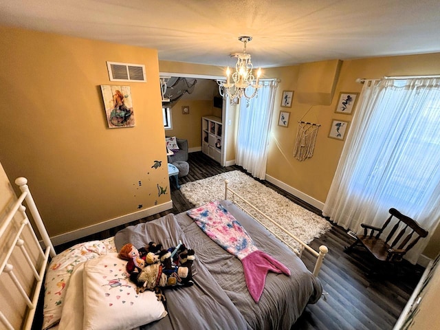 unfurnished bedroom featuring a chandelier, visible vents, baseboards, and wood finished floors