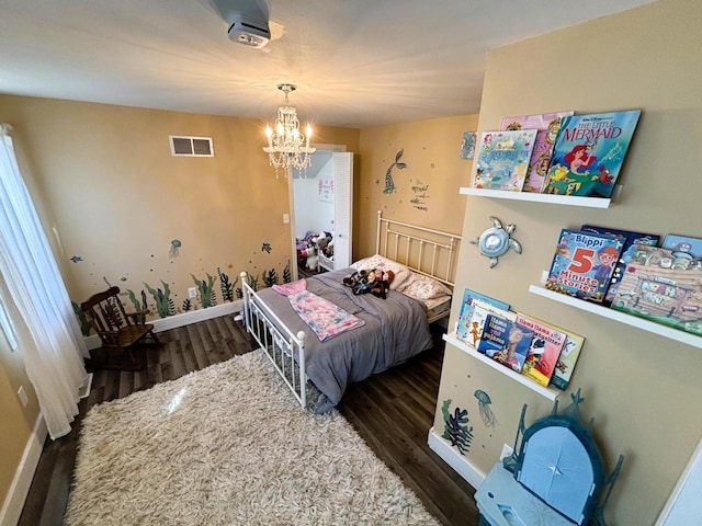 bedroom with a notable chandelier, visible vents, baseboards, and wood finished floors