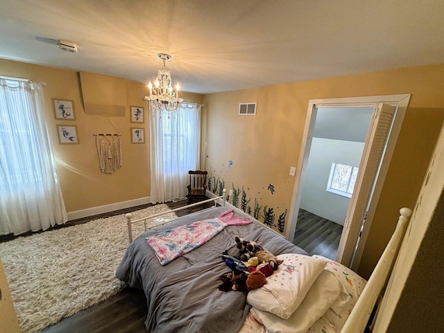 bedroom featuring a notable chandelier, wood finished floors, visible vents, and baseboards