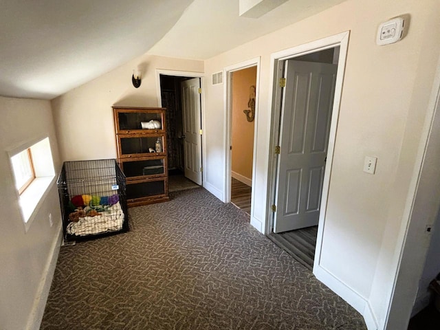 hallway with vaulted ceiling, baseboards, visible vents, and carpet floors